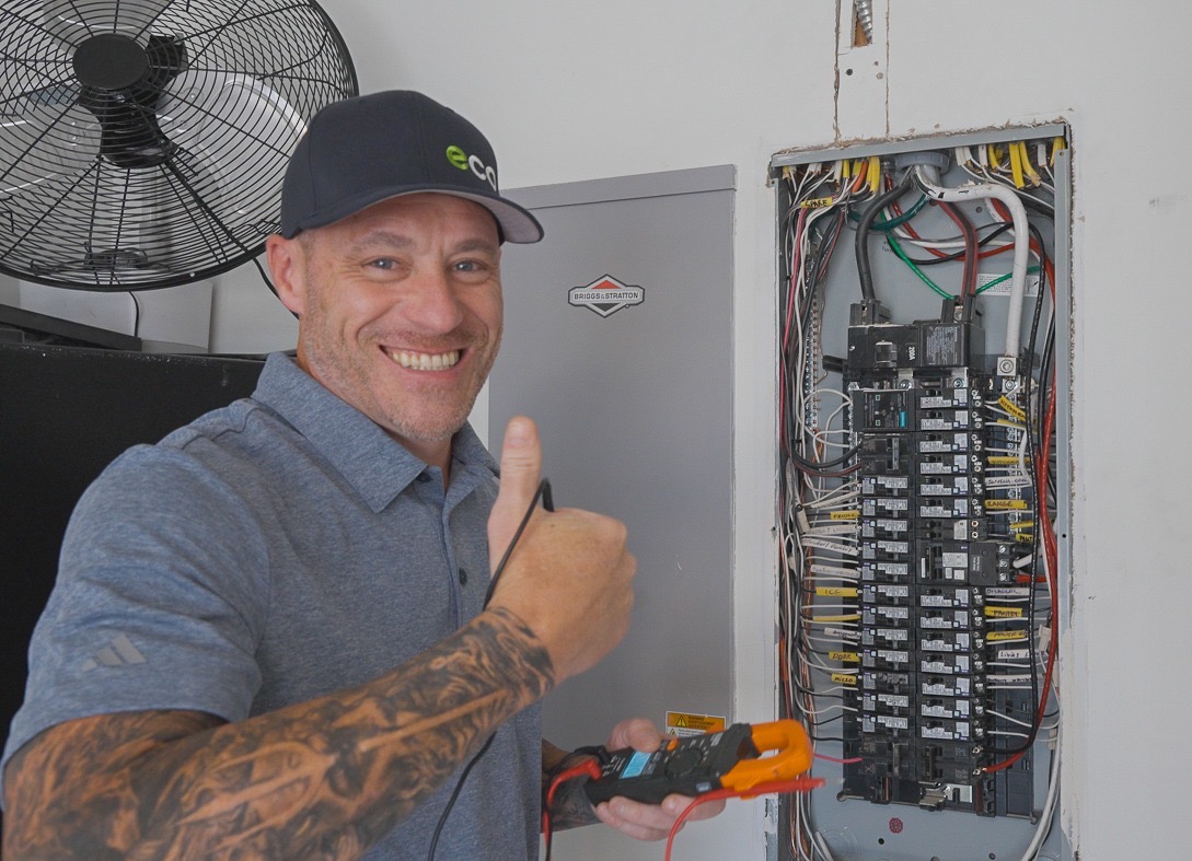 Smiling Eco Electric technician giving a thumbs up after servicing an electrical panel