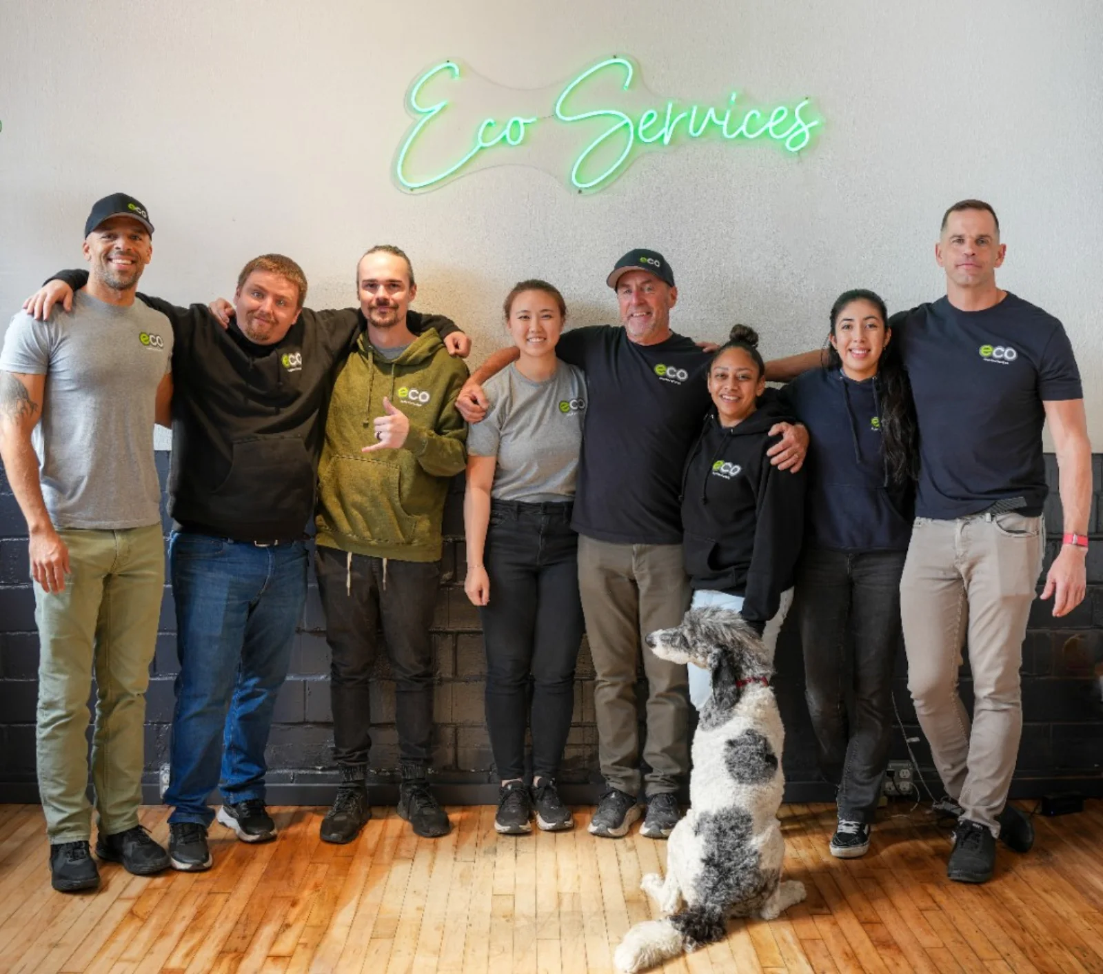 The Eco team and office dog under the Eco Services neon sign